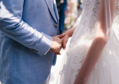Bruid en bruidegom houden elkaars hand vast tijdens ceremonie